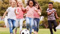 Group Of Children Playing Football With Friends In Park