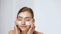 Face skin care. Woman applying facial cleanser on face closeup