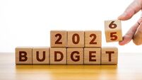 Hand flips wooden cube and changes inscription BUDGET 2025 to BUDGET 2026 against white background