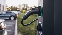 Electric car charging at plug in charging station in a public car park.