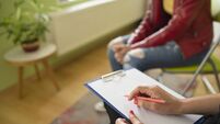 Close up of a female psychologist taking notes and a students knees