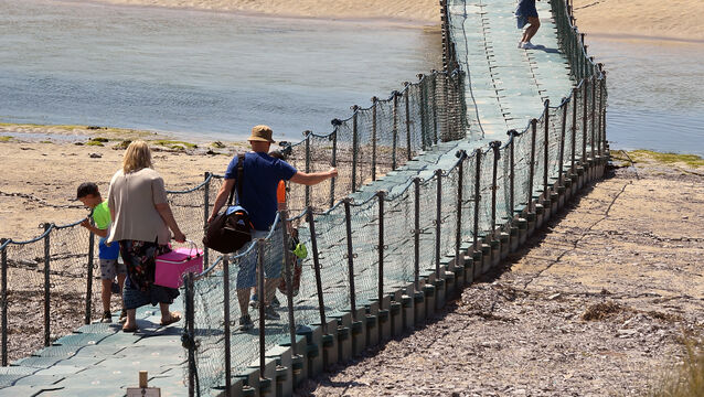 <p> Families crossing the pontoon as they head to the beach at Barleycove in West Cork. Picture Dan Linehan</p>