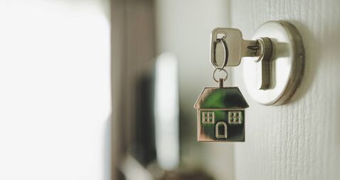 Open the door and door handle with a key and a keychain shaped house. Property investment and house mortgage financial real esta