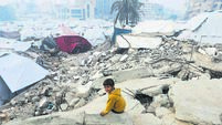 A Palestinian child sits amid the rubble of buildings destroyed in previous Israeli strikes, ahead of a ceasefire set to take ef