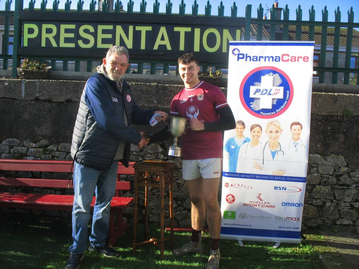 Seandún GAA Chairman Mick Buckley presents the U21B trophy to Bishopstown winning captain Daire Daly 