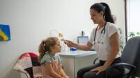 Female doctor is taking a child patient's temperature using a digital thermometer at pediatric office