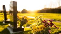Dusk at a winter's English cemetery seen with in-focus flowers in a burial plot.