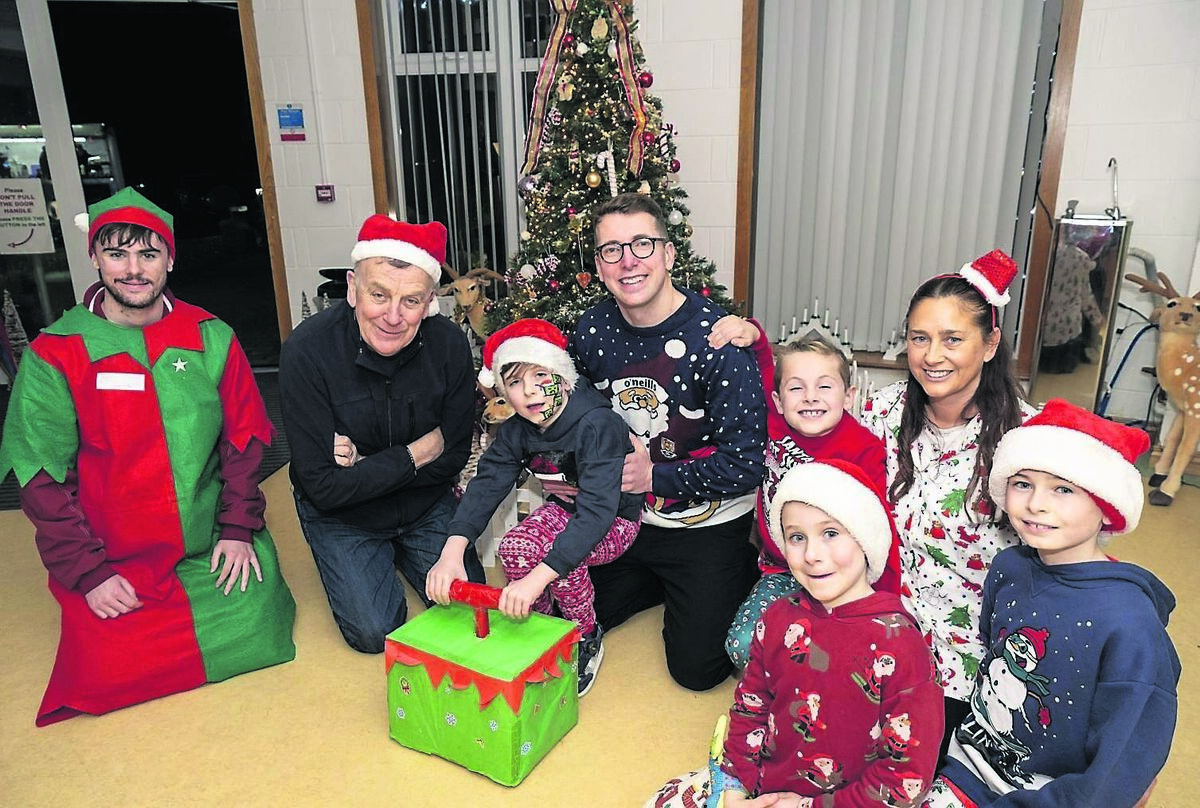 Daithí Murphy, 7, from Ballincollig helps CEO Padraig Mallon (second left) to turn on the Christmas lights at the Crann Centre, cheered on by his brothers Culann, 10, twins Tiarnán and Séamí, 8, parents Andrew and Caroline, and one of Santa’s elves.	Picture: Brian Lougheed
                    