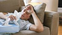 Man with a cold lying in sofa holding tissues