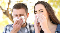 Sick couple sneezing together covering mouth with wipes in a park