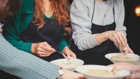 Group of people in a cooking class studio, adults preparing different dishes in the kitchen together, people in aprons learn on