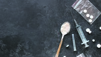 Drugs in the form of powder and tablets, a spoon and a syringe on a black background mockup