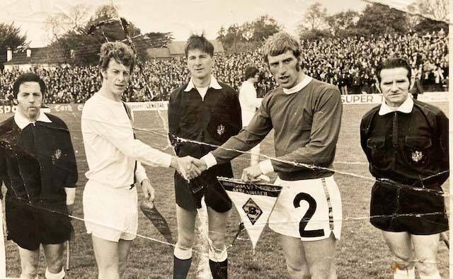 Referee Derry Barrett with assistants Frank Casey, left. and Sammy Spillane watch rival captains Hebert Wimmer (Borussia Monchengladbach), left, and Dave Bacuzzi (MFA Selection) exchange pennants before the association's 50th anniversary celebration match at Flower Lodge on Sunday, May 28th 1972 (pic: Finbarr Buckley)