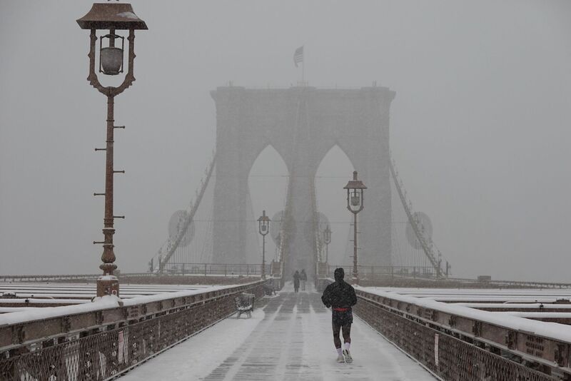 A person jogs across the Brooklyn Bridge as it snows on Sunday, Jan. 25, 2026, in New York. (AP Photo/Alyssa Goodman)