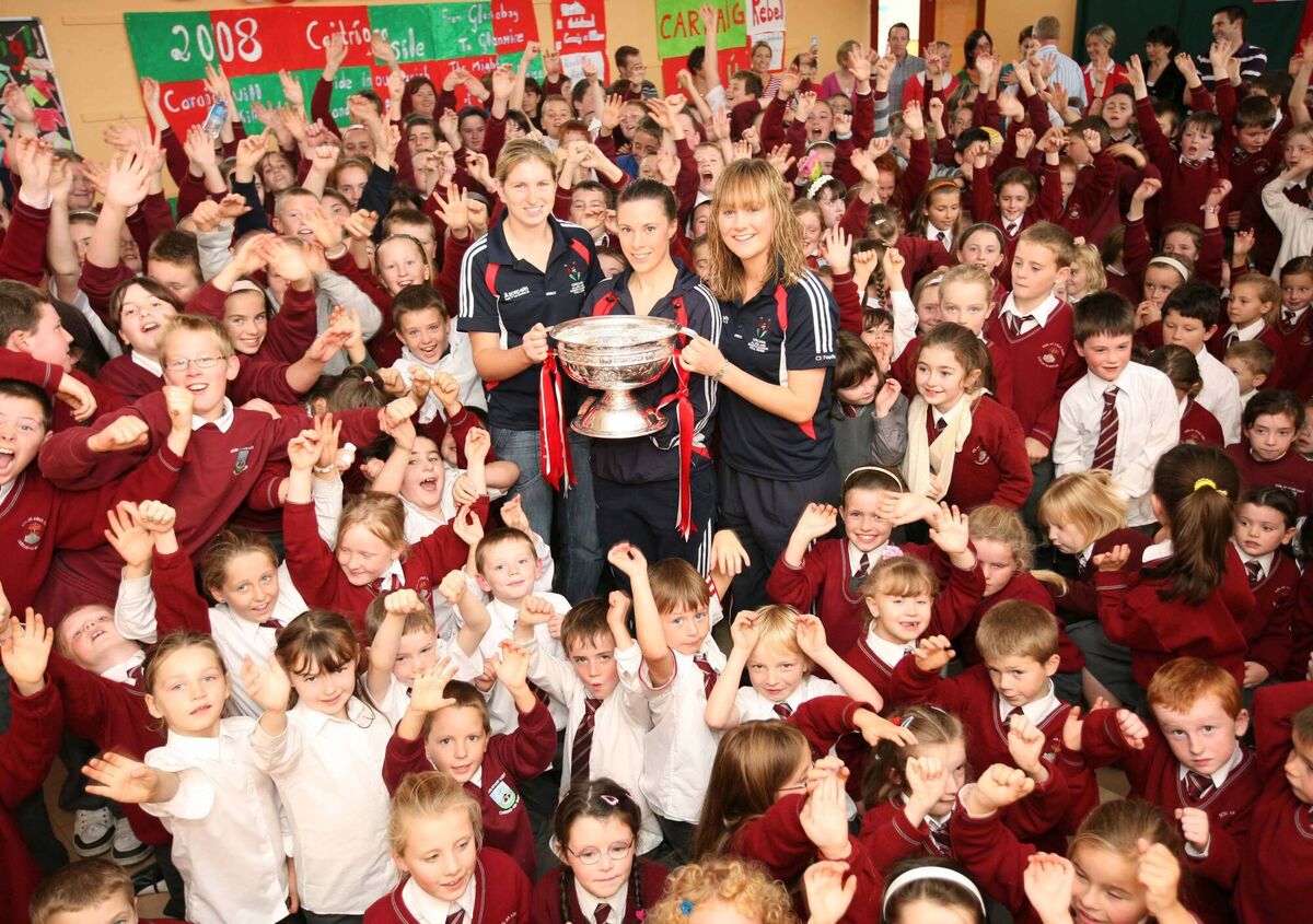 Cork Camogie players, Amanda O'Regan, Caitriona Foley and Sile Burns hold the O'Duffy Cup amid a sea of young fans at Scoil an Athair Tadhg, Carrignavar. /Pic Darragh Kane