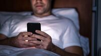 Phone in bed at night. Man with smartphone before sleeping. Secret texting, cheating or working late. Happy guy browsing online