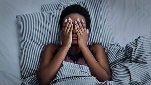 African american girl closed eyes with hands in bed