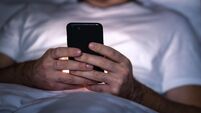 Phone in bed at night. Man with smartphone before sleeping. Secret texting, cheating or working late. Happy guy browsing online