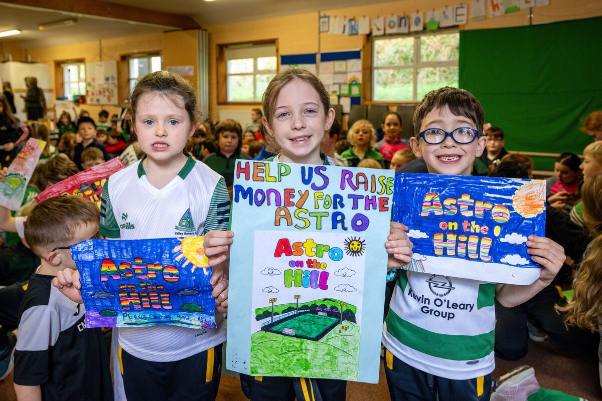 Pupils Muireann Mulqueen, Ríona Hickey, and Sean Cronin holding their handmade signs aloft at the launch of fundraising campaign.
