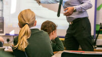 Primary school girls are taught during a lesson by a male teacher