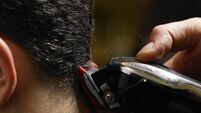 Barber cutting man's hair, close-up of electric razor, side view