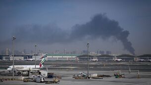 <p>A plume of smoke caused by an Iranian strike is seen in the background as Emirates planes are parked at Dubai International Airport after its closure in Dubai, United Arab Emirates. Picture: AP Photo/Altaf Qadri.</p>