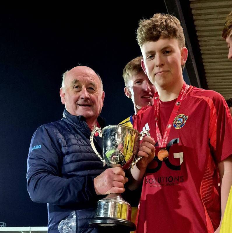 Douglas Hall captain James O’Flaherty receives the U19 League Cup from Mr Richie Browne of the Cork Youth League at Munster FA Turner’s Cross last Friday night.
